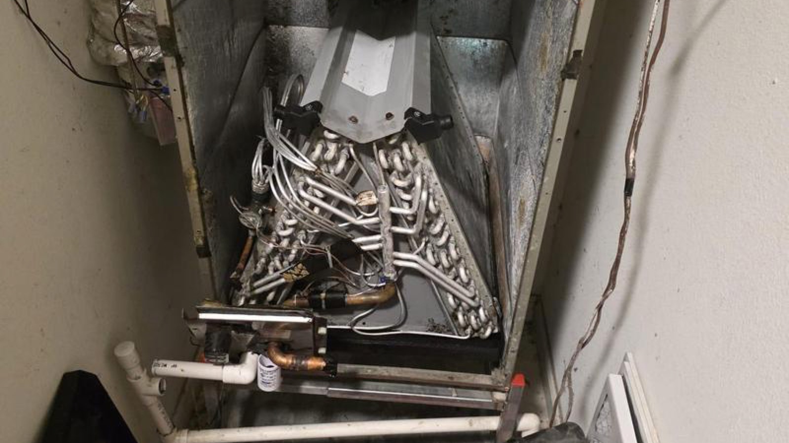 Open indoor HVAC cabinet showing the coil and service area during repair